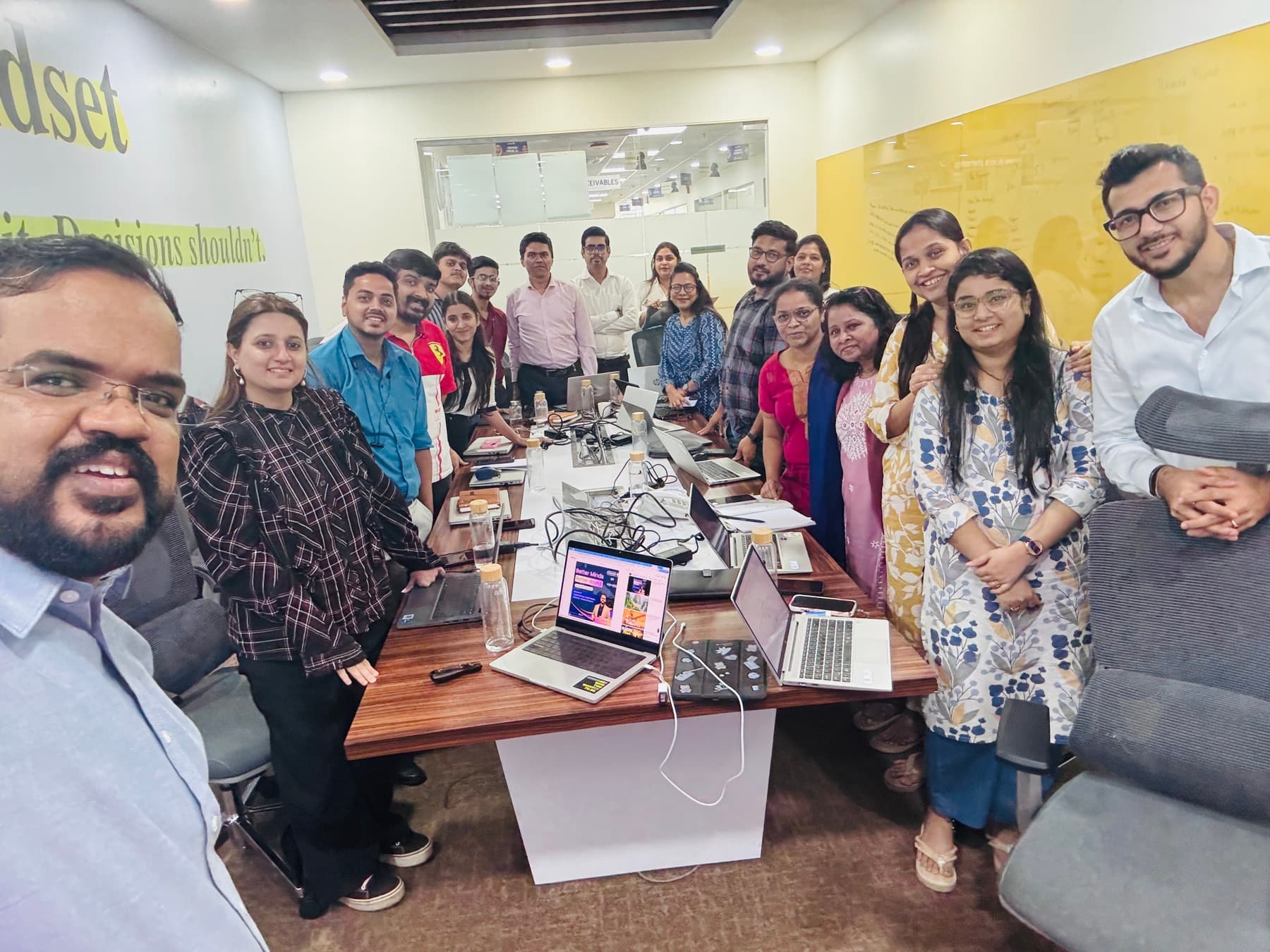 A selfie with a workshop team around a table of laptops.