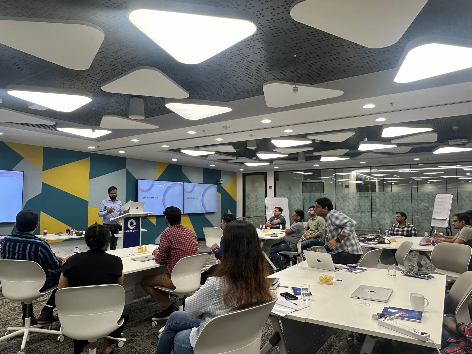 Amit Kumar Soni presenting from a lectern in a colourful corporate learning space.