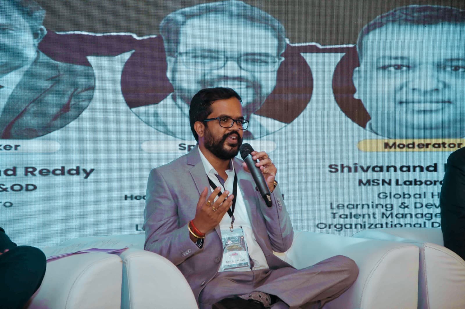 Amit Kumar Soni speaking on a conference panel, microphone in hand.