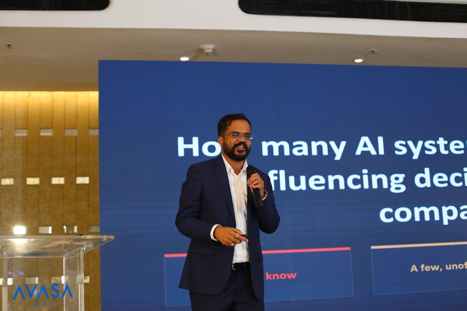 Amit Kumar Soni speaking with a microphone in front of a large presentation screen.