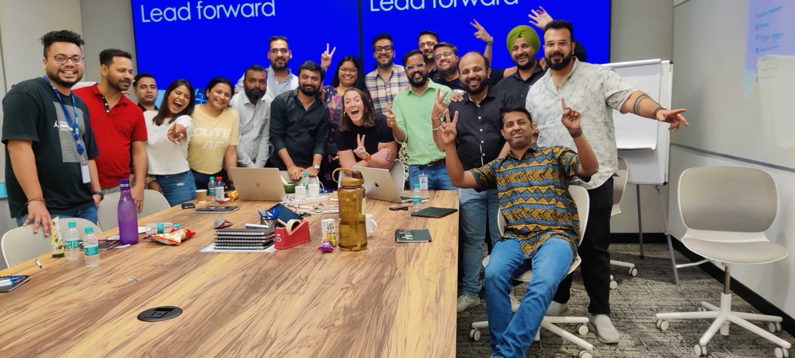 A smiling team gathered around a table after an on-site enablement session with Amit Kumar Soni.