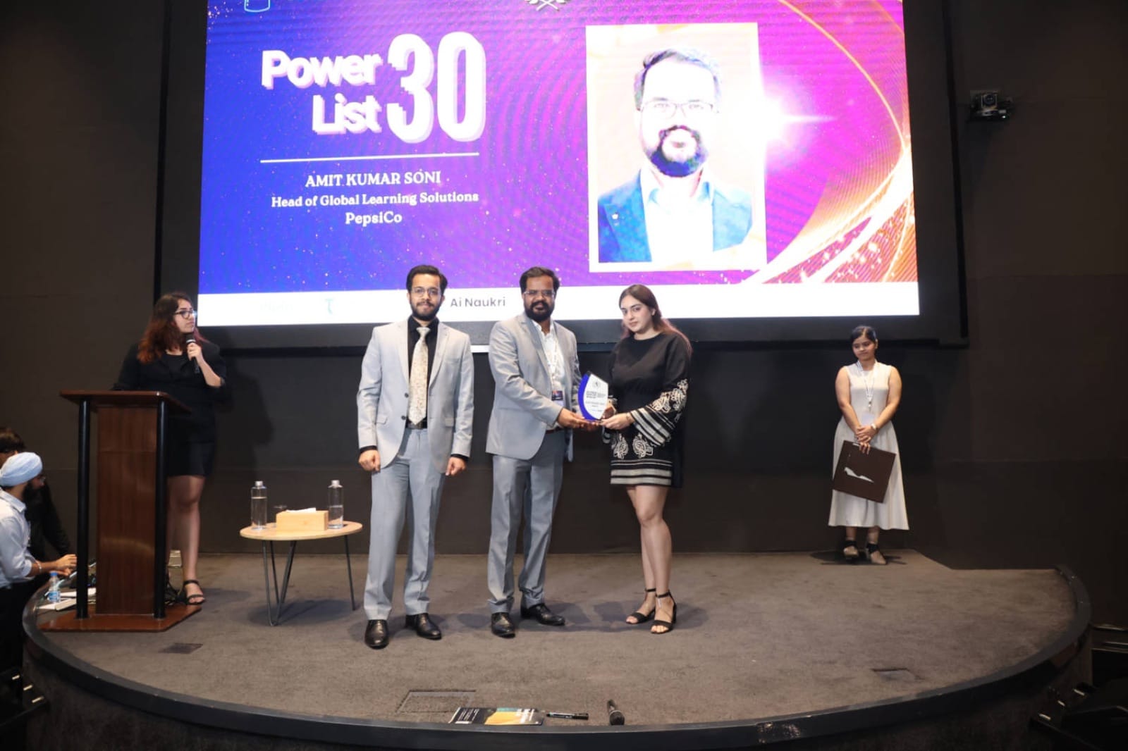 Amit Kumar Soni on stage accepting the AI World Power 30 recognition, with his profile on the screen behind.