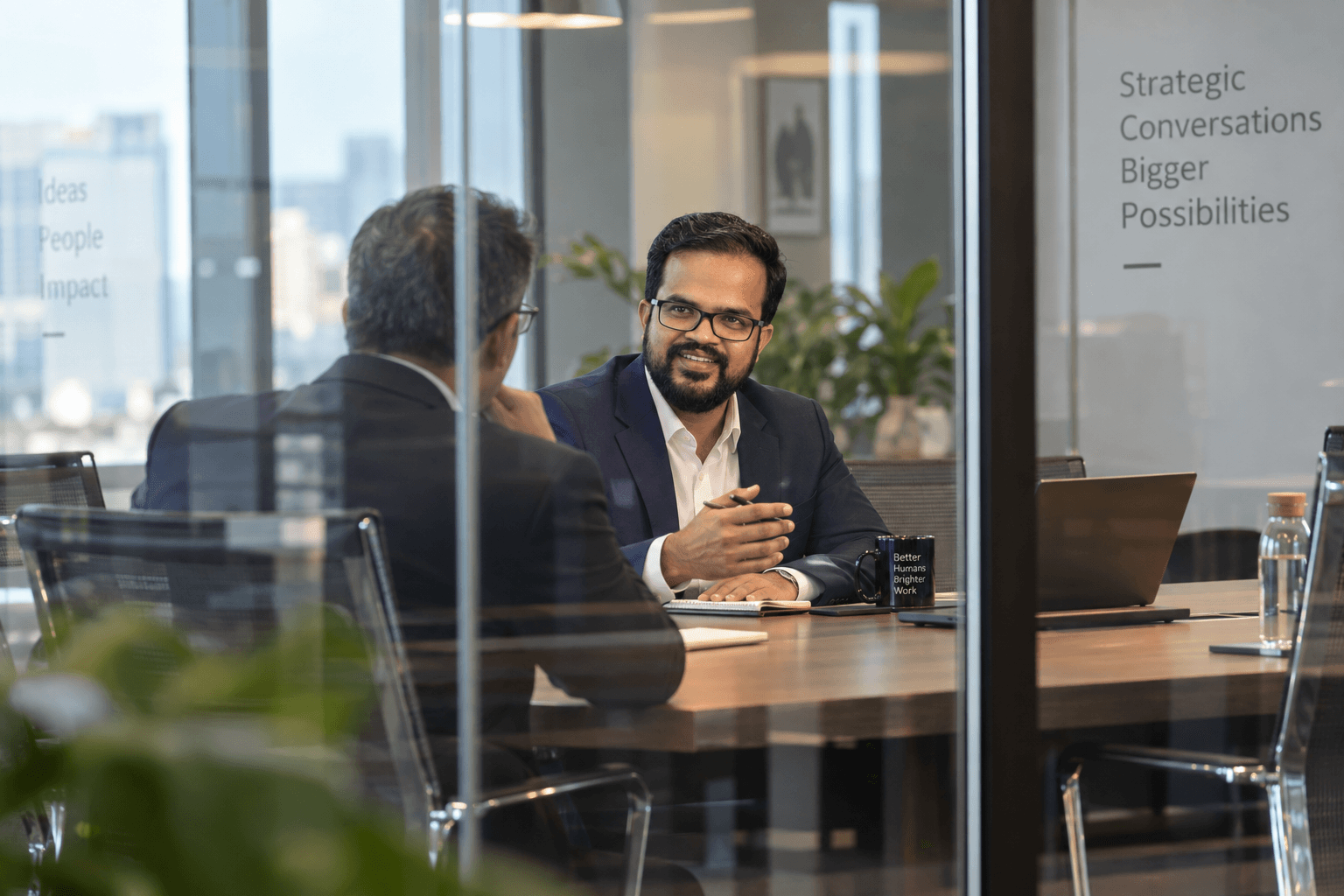 Amit Kumar Soni in a one-to-one coaching conversation in a glass-walled meeting room.